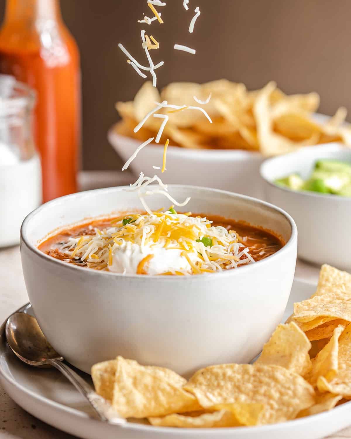 cheese being sprinkled onto a bowl of Taco Soup