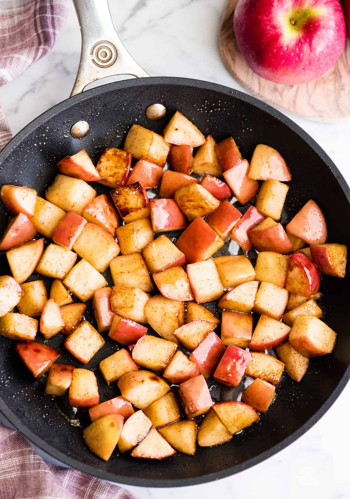 These Stovetop Sautéed Cinnamon Apples taste like a warm apple pie, but they come together in 5 minutes and are SO much healthier! This recipe is gluten-free, dairy-free, refined sugar free, vegan AND paleo! Perfect for breakfast, a snack, or dessert! #apples #stovetop #cinnamon #healthyrecipe #dessert #breakfast #snack #paleo #vegan #glutenfree #dairyfree #refinedsugarfree overhead view of sautéed cinnamon apples in a black nonstick fry pan