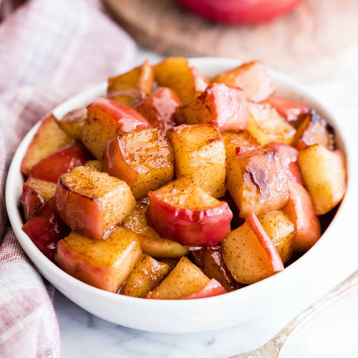 These Stovetop Sautéed Cinnamon Apples taste like a warm apple pie, but they come together in 5 minutes and are SO much healthier! This recipe is gluten-free, dairy-free, refined sugar free, vegan AND paleo! Perfect for breakfast, a snack, or dessert! #apples #stovetop #cinnamon #healthyrecipe #dessert #breakfast #snack #paleo #vegan #glutenfree #dairyfree #refinedsugarfree Overhead view of sautéed cinnamon apples in a white bowl