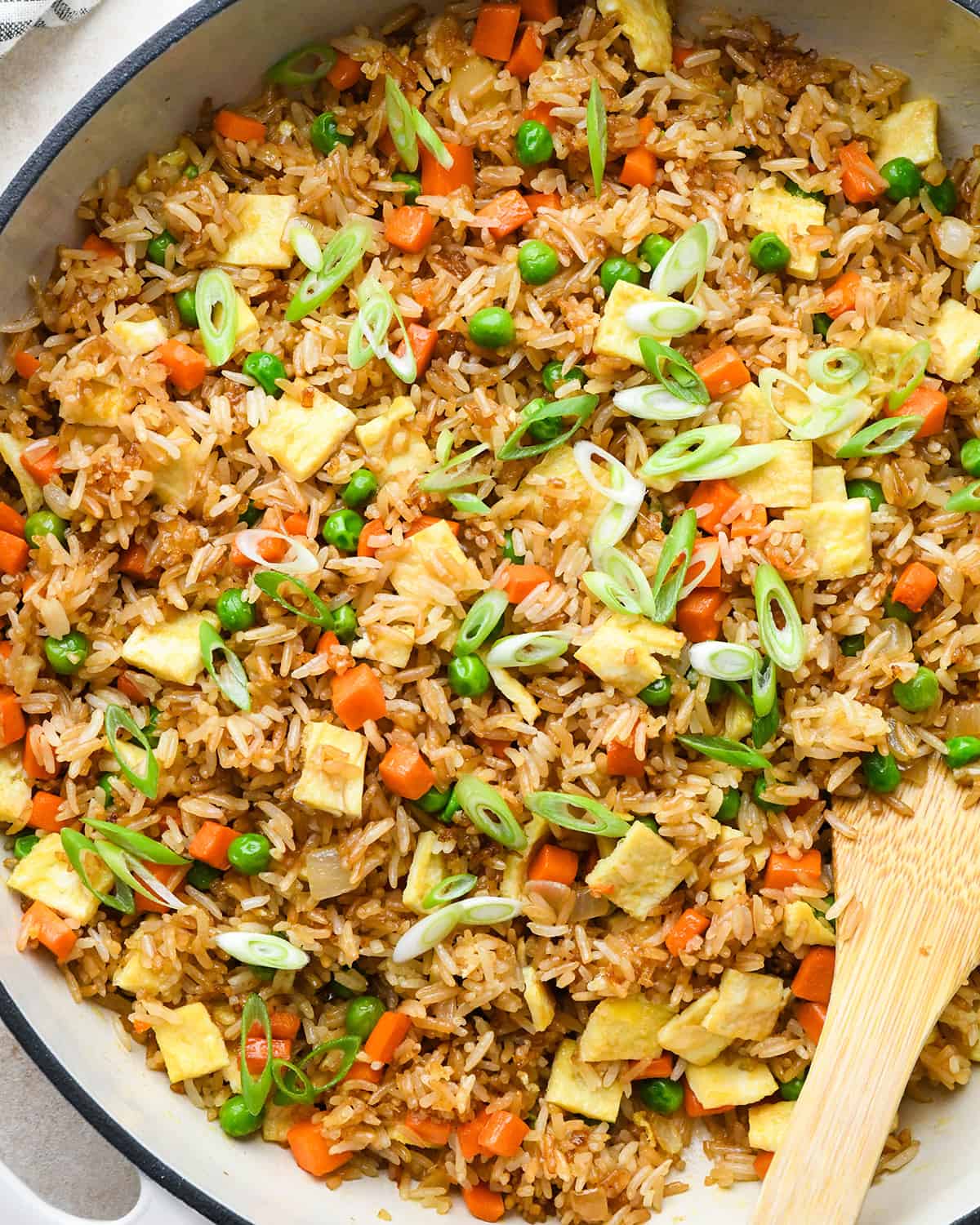 This easy vegetable fried rice recipe is better than takeout! It only takes 20 minutes to make the best fried rice recipe that's flavorful, healthy and loaded with eggs and veggies! Best Fried Rice Recipe in a pan with a wooden spoon