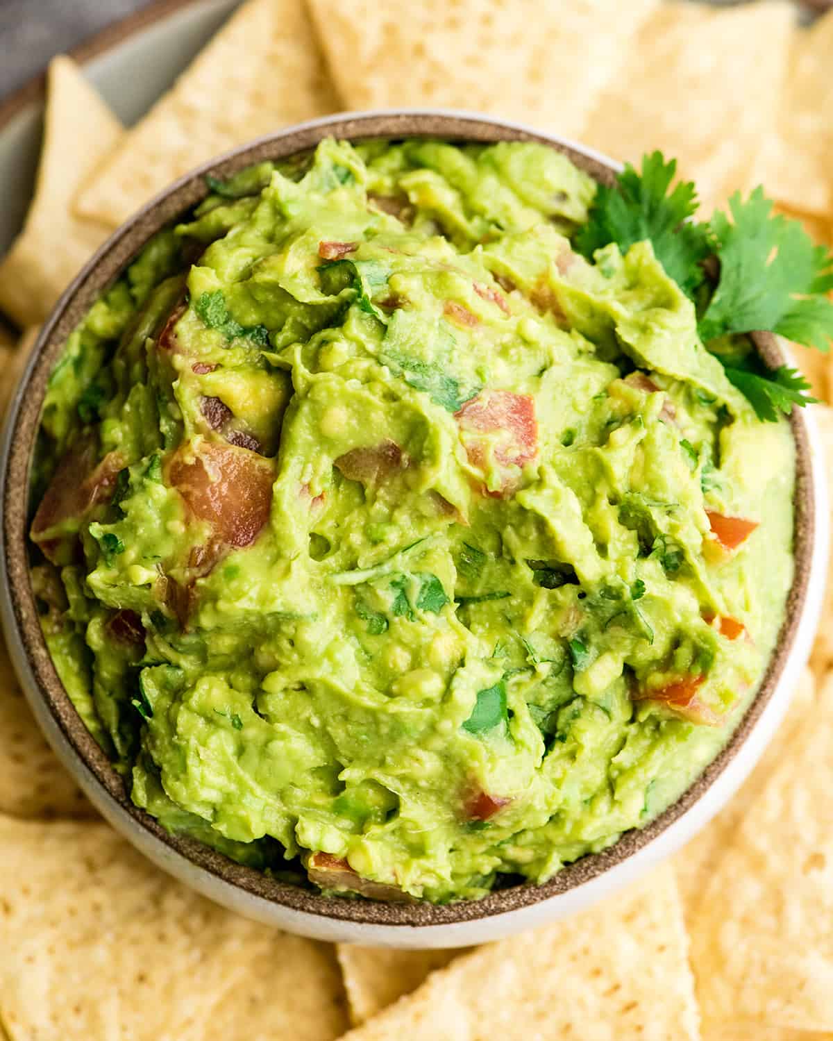 This quick & easy guacamole recipe is made with a handful of healthy ingredients and is ready in 5 minutes! This simple guacamole dip is our favorite appetizer and we always make it on taco nights! Watch the video to learn how to make this guacamole recipe! #guacamole #guacamolerecipe #tacos #appetizer #dip Overhead view of easy guacamole recipe in a bowl surrounded by chips