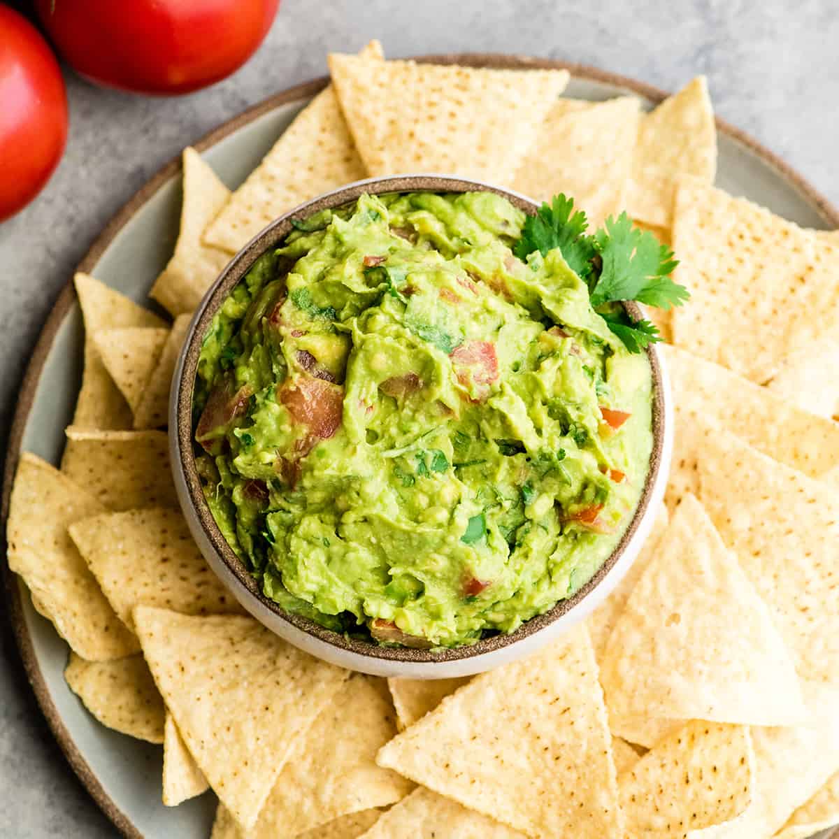 This quick & easy guacamole recipe is made with a handful of healthy ingredients and is ready in 5 minutes! This simple guacamole dip is our favorite appetizer and we always make it on taco nights! Watch the video to learn how to make this guacamole recipe! #guacamole #guacamolerecipe #tacos #appetizer #dip overhead view of a bowl of guacamole surrounded by chips