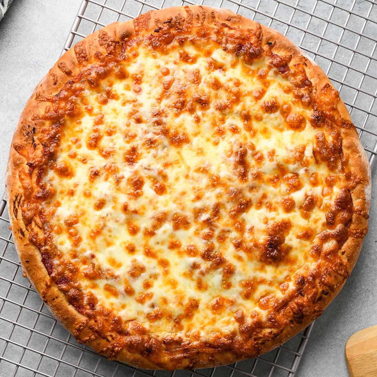 a baked pizza on a wire cooling rack on a gray surface