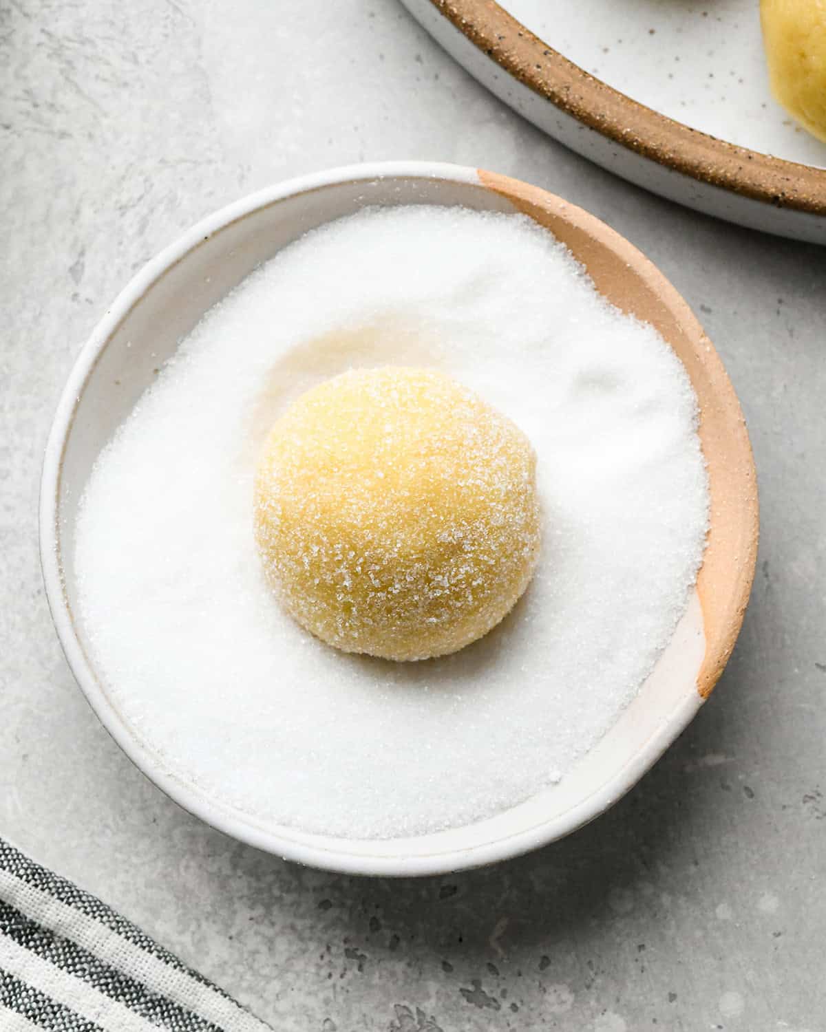 How to Make Easy Sugar Cookies - a ball of dough in a bowl of sugar after rolling