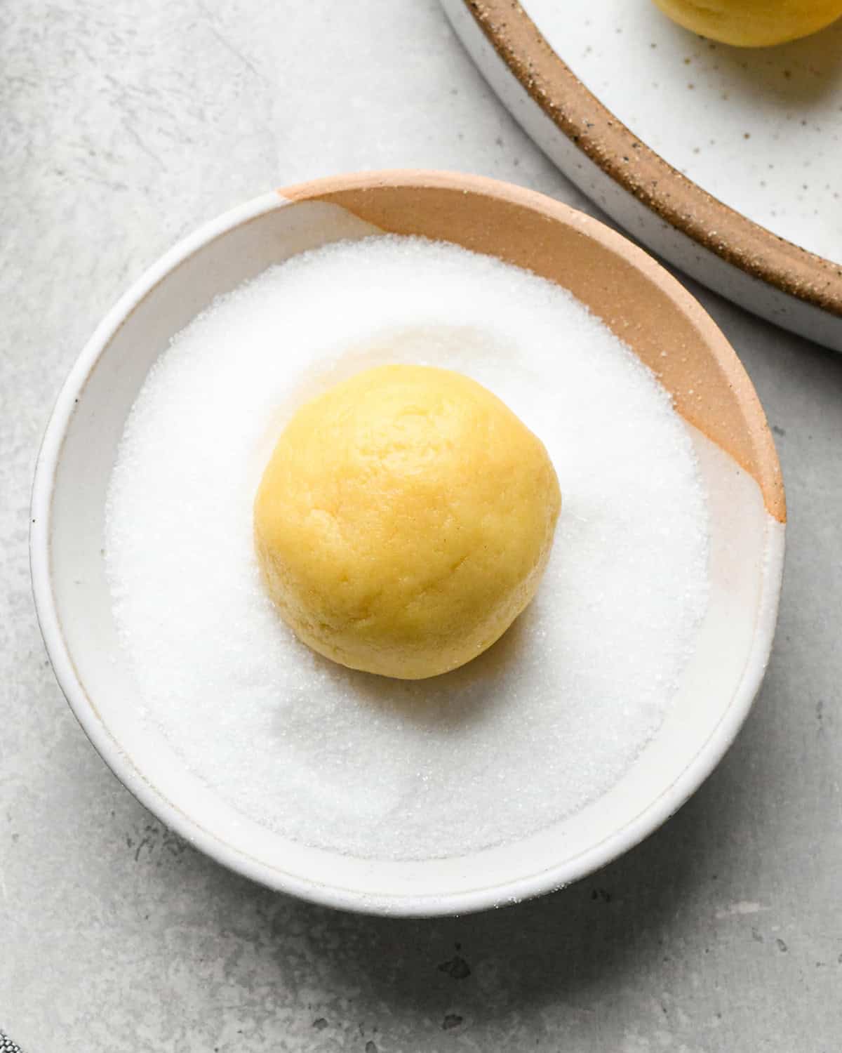 How to Make Easy Sugar Cookies - a ball of dough in a bowl of sugar before rolling