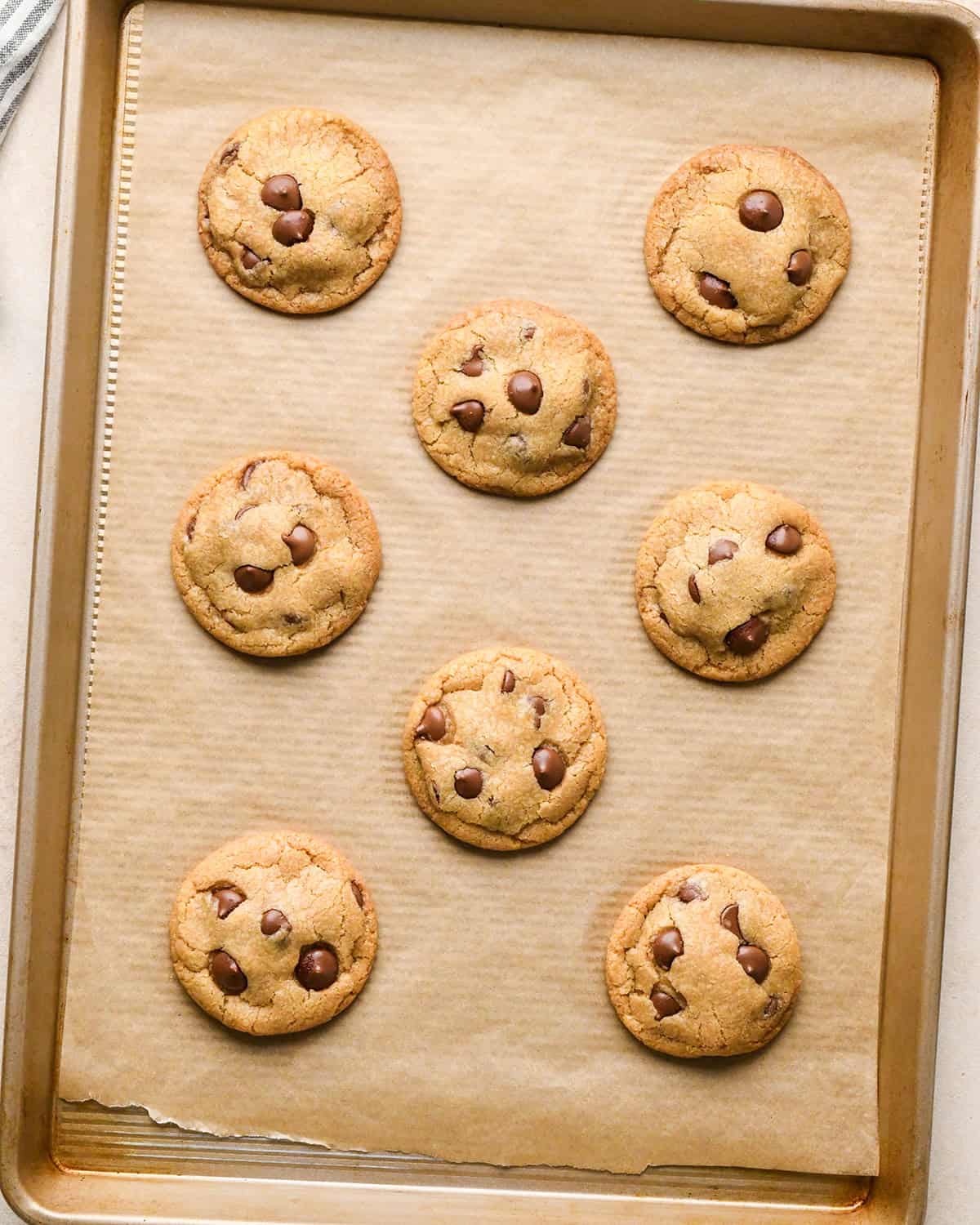 8 eggless chocolate chip cookies on a baking sheet after baking