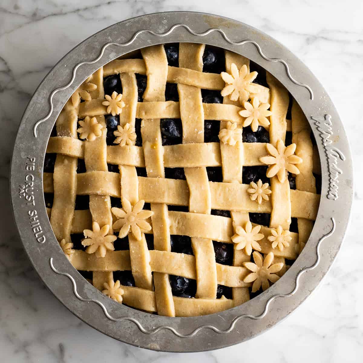 overhead view of an unbaked pie with a pie crust shield protecting the outer Pie Crust