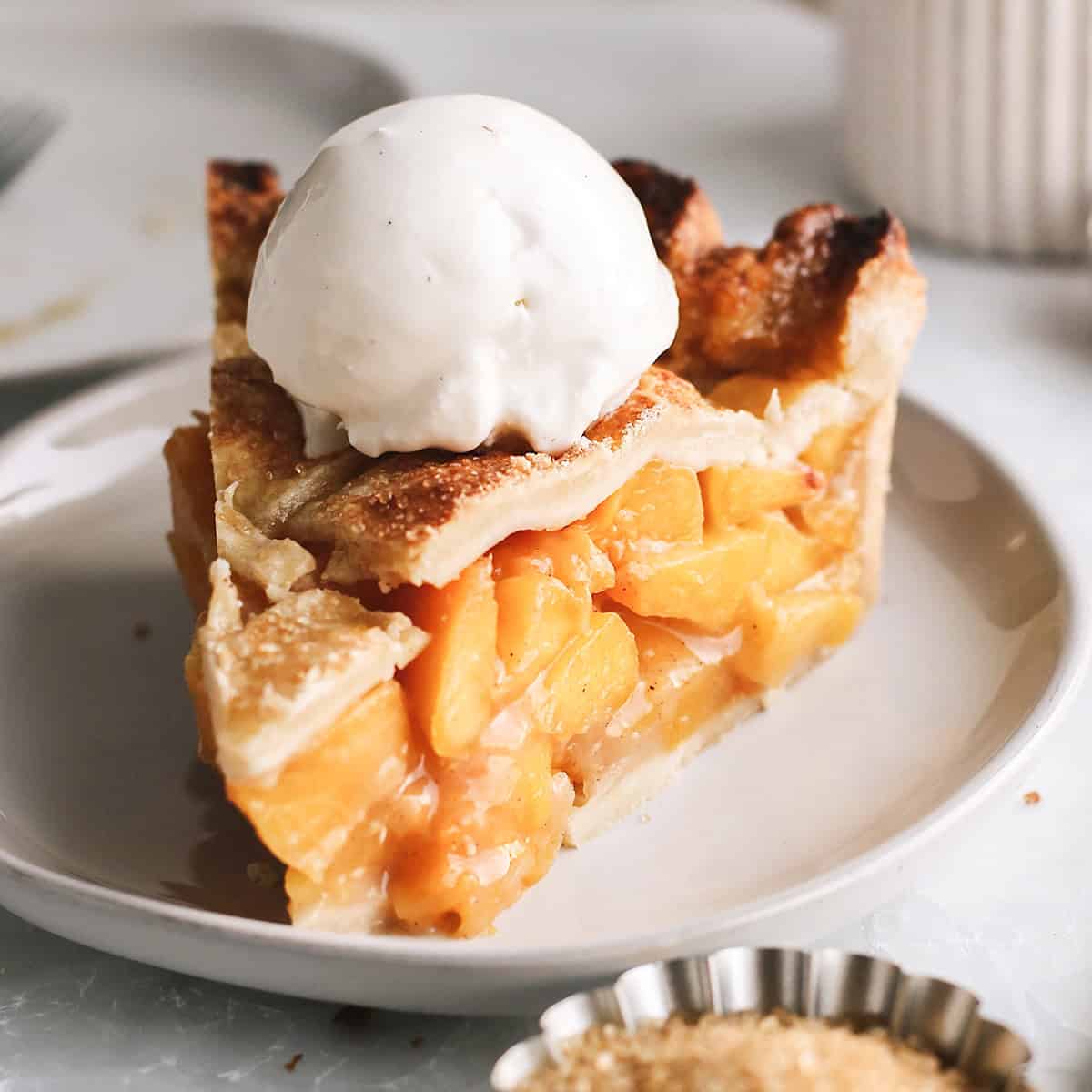 a slice of peach pie on a plate with vanilla ice cream on top