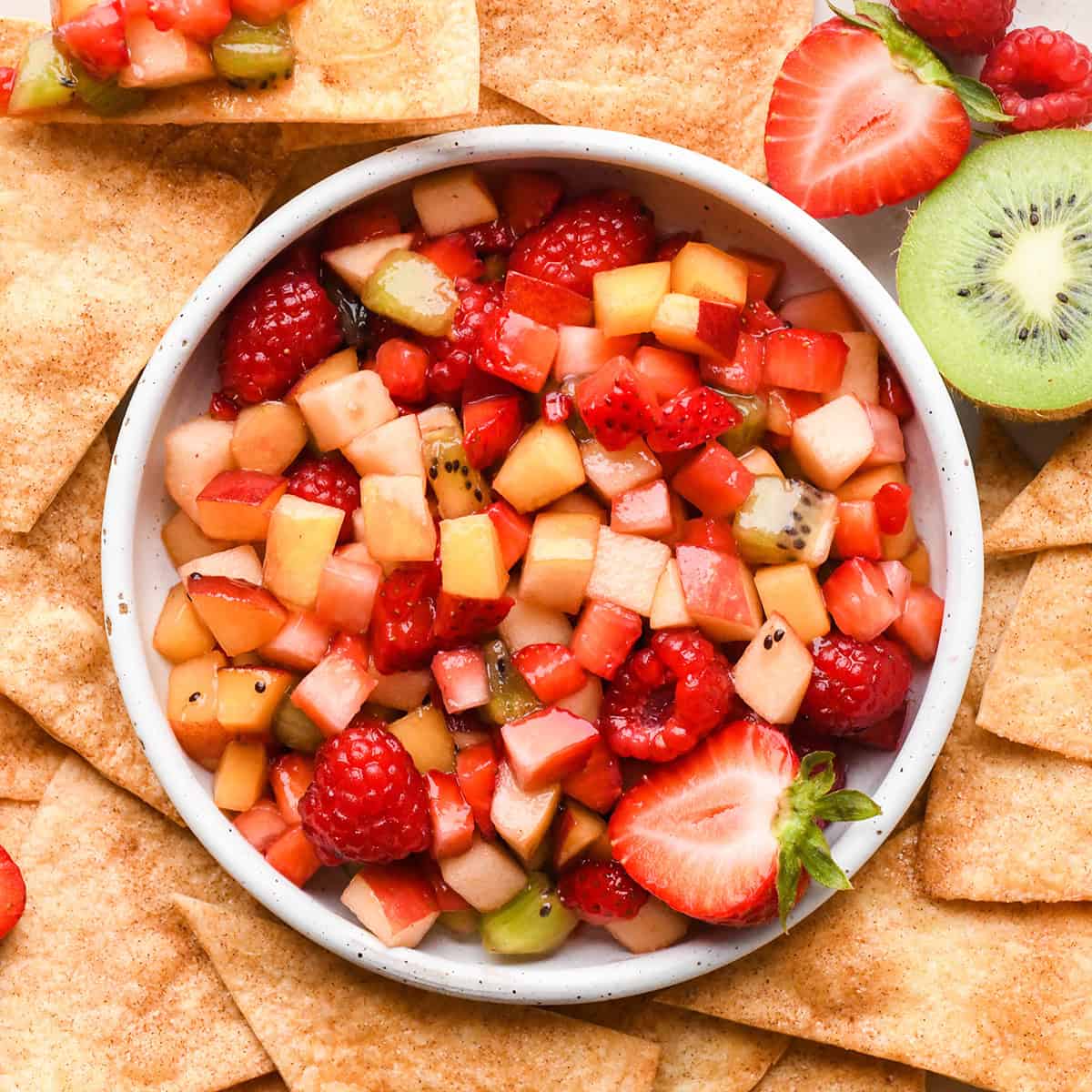 a bowl of Fruit Salsa with Cinnamon Chips surrounding it