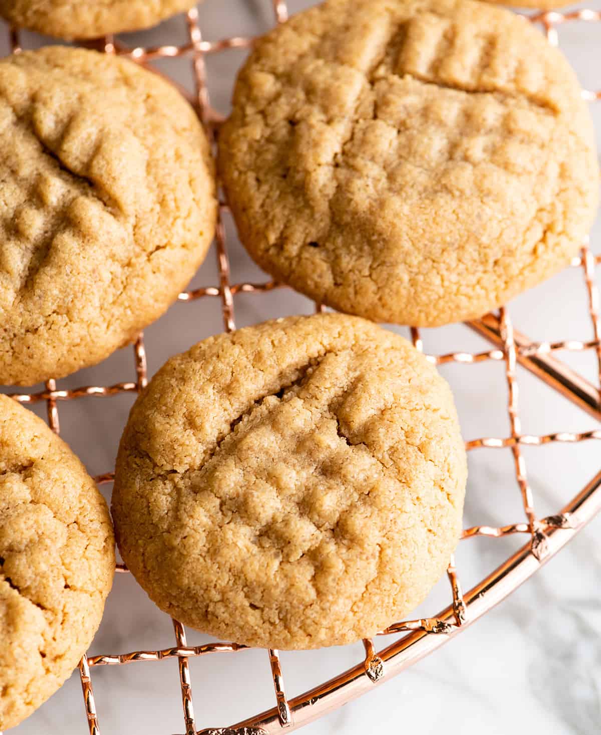 These Flourless Peanut Butter Cookies are easy to make with 4 ingredients in 15 minutes! These gluten-free peanut butter cookies are so good no one can tell they're made without flour or butter! overhead view of 4 flourless peanut butter cookies on a cooling rack