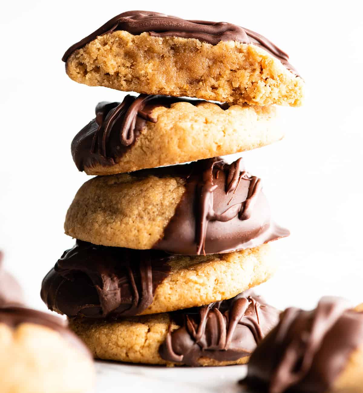 These Flourless Peanut Butter Cookies are easy to make with 4 ingredients in 15 minutes! These gluten-free peanut butter cookies are so good no one can tell they're made without flour or butter! front view of a stack of 5 gluten-free peanut butter cookies dipped in chocolate