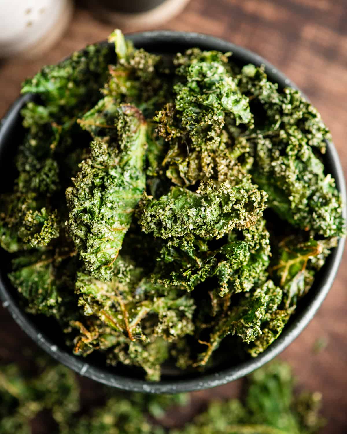 This is the best Baked Kale Chips recipe ever! Homemade crispy kale chips are a delicious, healthy snack made with only five ingredients. Roasting kale chips in the oven keeps them crispy for days! overhead view of baked kale chips in a bowl