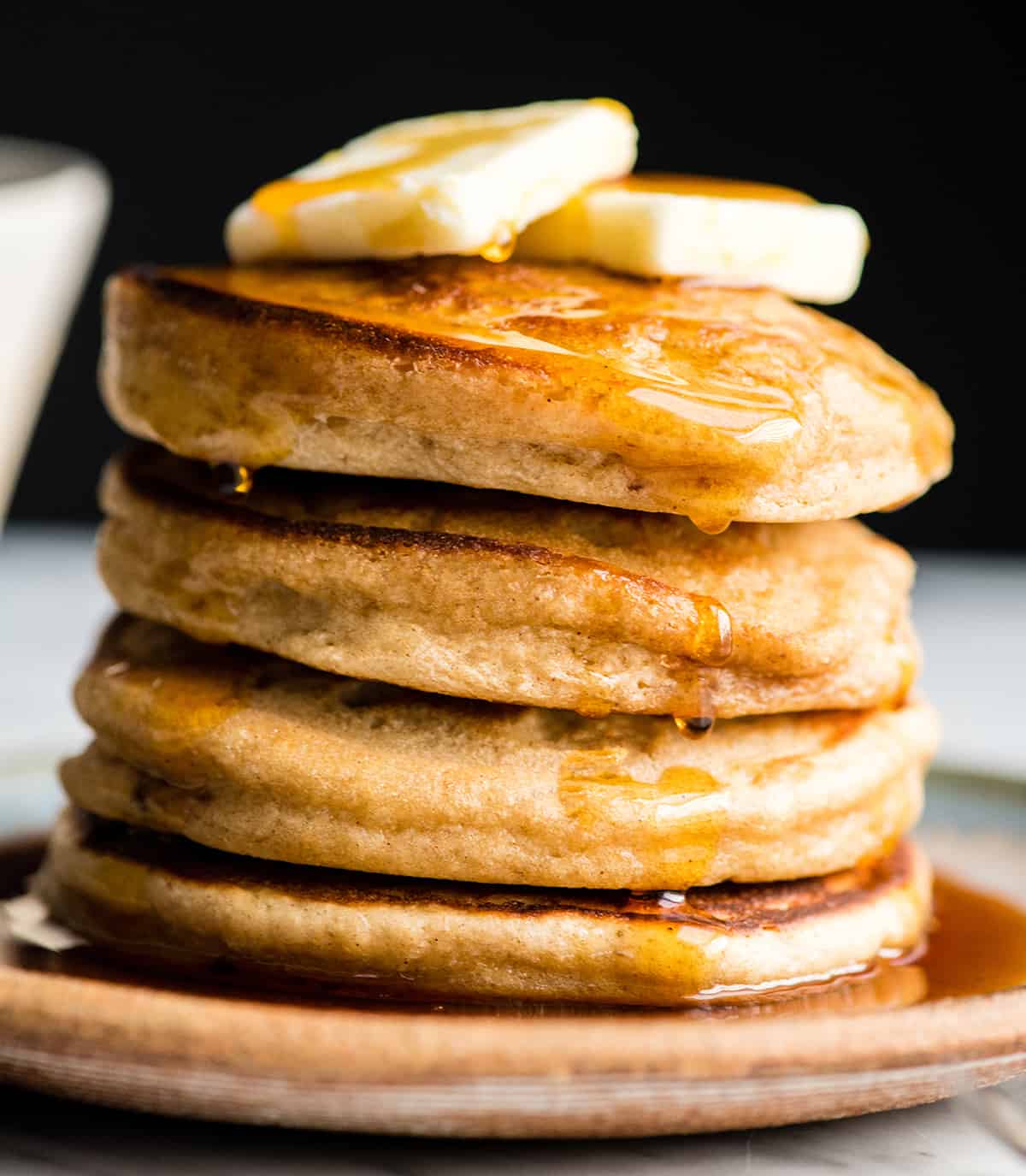 Healthy Greek Yogurt Pancakes Recipe! An easy, one-bowl, delicious and nutritious breakfast recipe that your whole family will love! Freezer-friendly with gluten-free and refined sugar free options!! #easybreakfast #pancakes #recipe #greekyogurt #breakfast #vitamix #healthy Front view of a stack of four Greek Yogurt Pancakes with butter on top and maple syrup