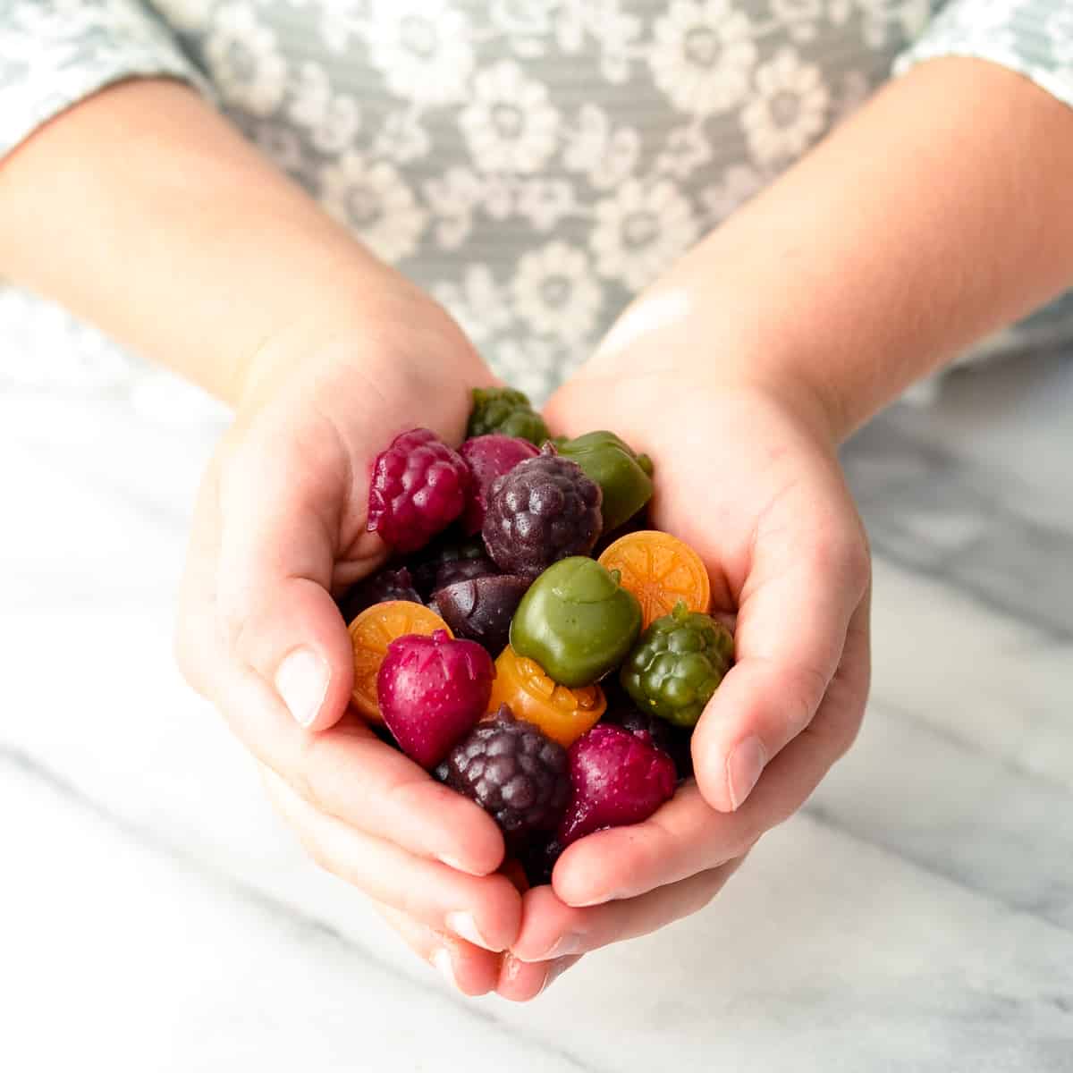 Homemade Fruit Snacks recipe made with whole fruits & vegetables! A healthy, high-protein snack loaded with nutrients made in the blender! #paleo #glutenfree #grainfree #dairyfree #refinedsugarfree #healthysnack #fruitsnacks #homemade #kidfriendly #snacktime Kid's hands holding a handful of Homemade Fruit Snacks recipe