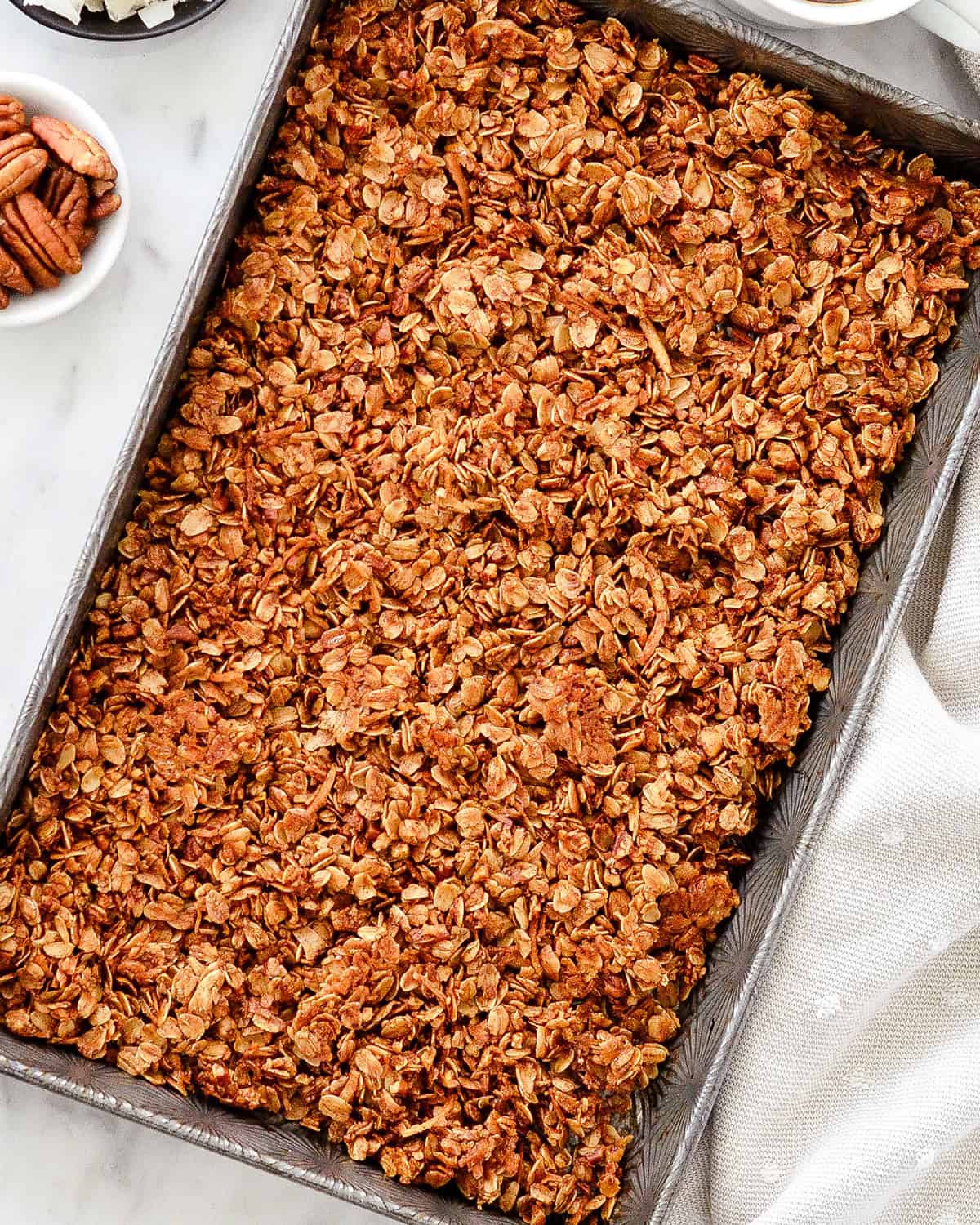 This Healthy Homemade Granola Recipe is easy to make with only 8 ingredients in 30 minutes! It's gluten-free, dairy-free vegan and has no refined sugar! The perfect healthy breakfast or snack! How to Make Homemade Granola - baked granola in a baking sheet