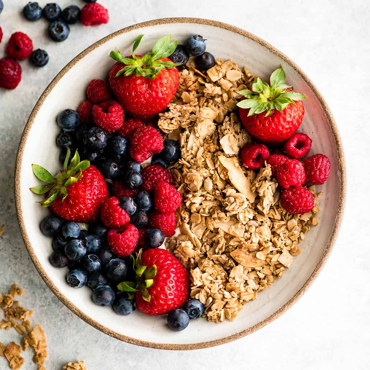 This Healthy Homemade Granola Recipe is easy to make with only 8 ingredients in 30 minutes! It's gluten-free, dairy-free vegan and has no refined sugar! The perfect healthy breakfast or snack! overhead view of a bowl of healthy homemade granola with berries
