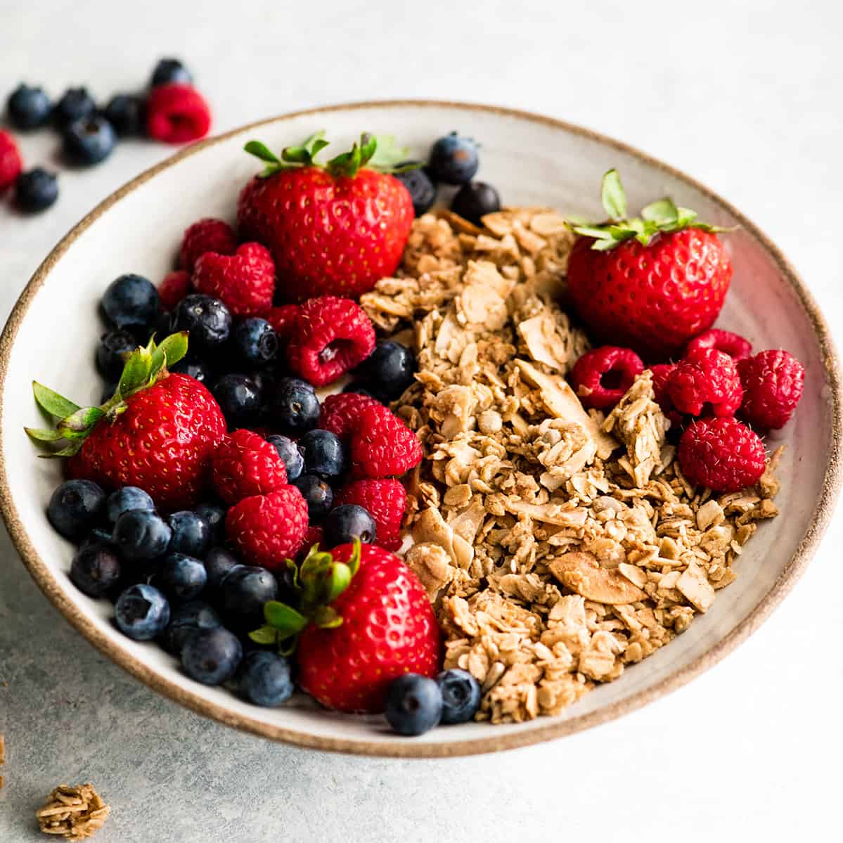 This Healthy Homemade Granola Recipe is easy to make with only 8 ingredients in 30 minutes! It's gluten-free, dairy-free vegan and has no refined sugar! The perfect healthy breakfast or snack! front view of a bowl of homemade granola recipe with berries
