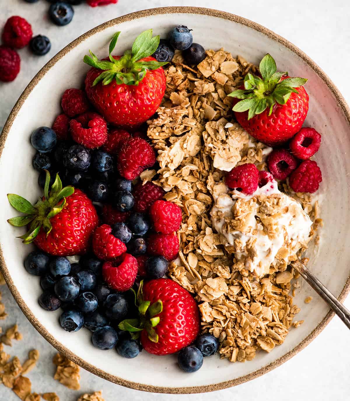 This Healthy Homemade Granola Recipe is easy to make with only 8 ingredients in 30 minutes! It's gluten-free, dairy-free vegan and has no refined sugar! The perfect healthy breakfast or snack! overhead view of a spoon taking a bite of homemade granola