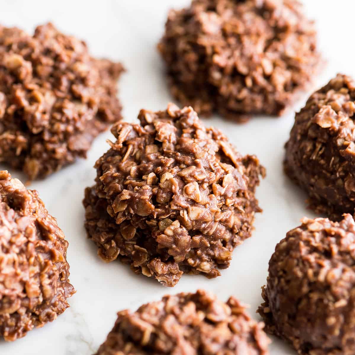 Healthy No-Bake Chocolate Peanut Butter Cookies! Made with only 8 good-for-you ingredients & ready in 30 minutes, they're a delicious treat you can feel great about eating! 7 healthy no bake cookies on a marble surface