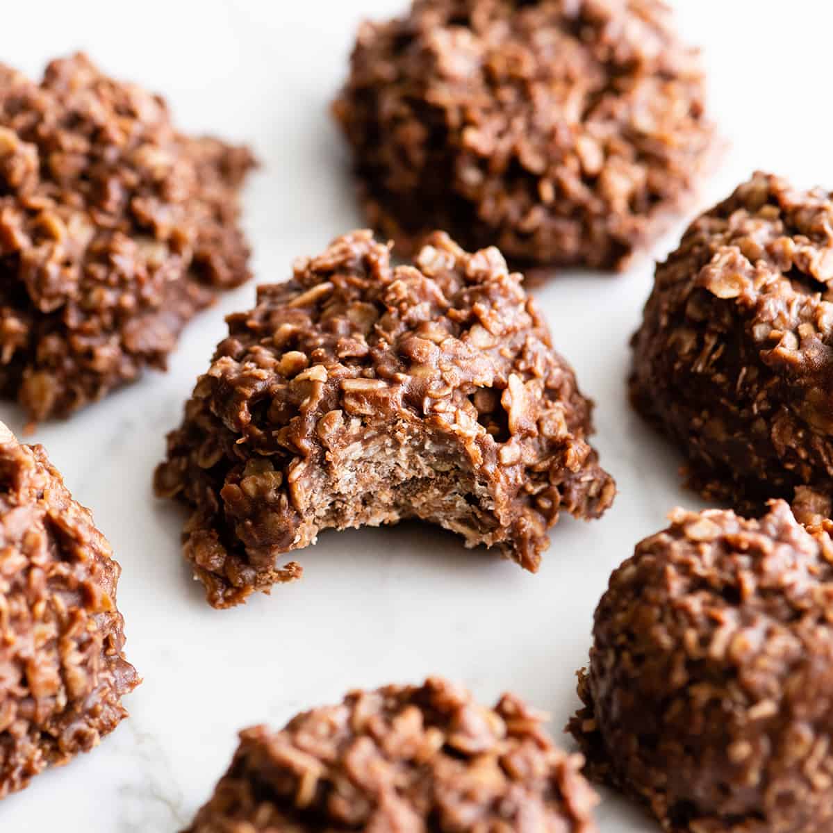 front view of a healthy no bake cookie with a bite taken out of it surrounded by other cookies