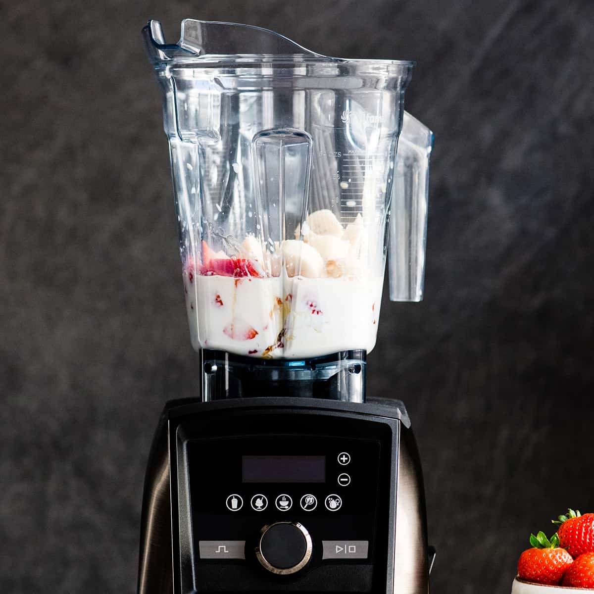 The BEST strawberry banana smoothie recipe ever! It's easy (ready in less than 5 minutes), healthy, and made with yogurt so it's full of protein! It's the perfect snack or breakfast! #smoothie #strawberrybananasmoothie #strawberry #banana #breakfast #snack #vitamix Front view of a Vitamix blender with the ingredients in it to make a Strawberry Banana Smoothie before blending