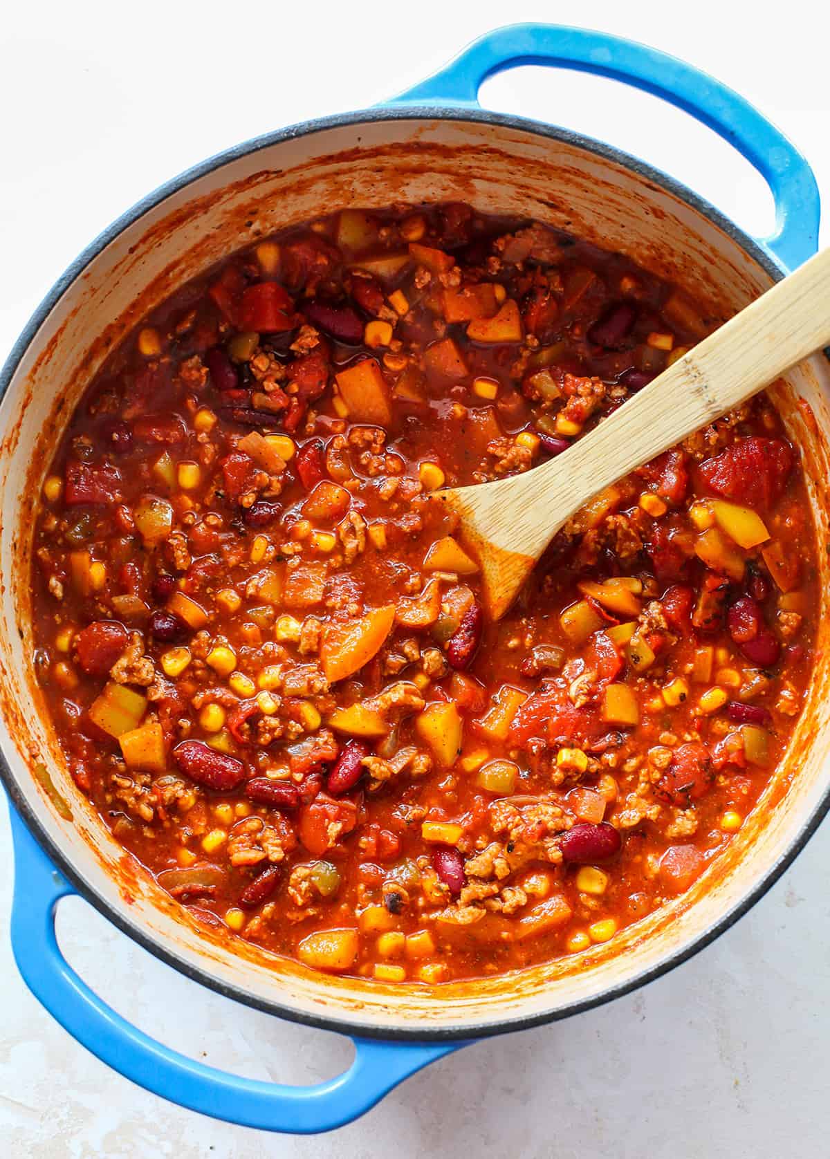 This Healthy Turkey Chili recipe is easy to make in 30 minutes on the stovetop. Turkey chili is loaded with protein and veggies and bursting with flavor thanks to a homemade spice mixture. A nutritious and cozy fall meal. overhead photo of a pot of turkey chili with a spoon