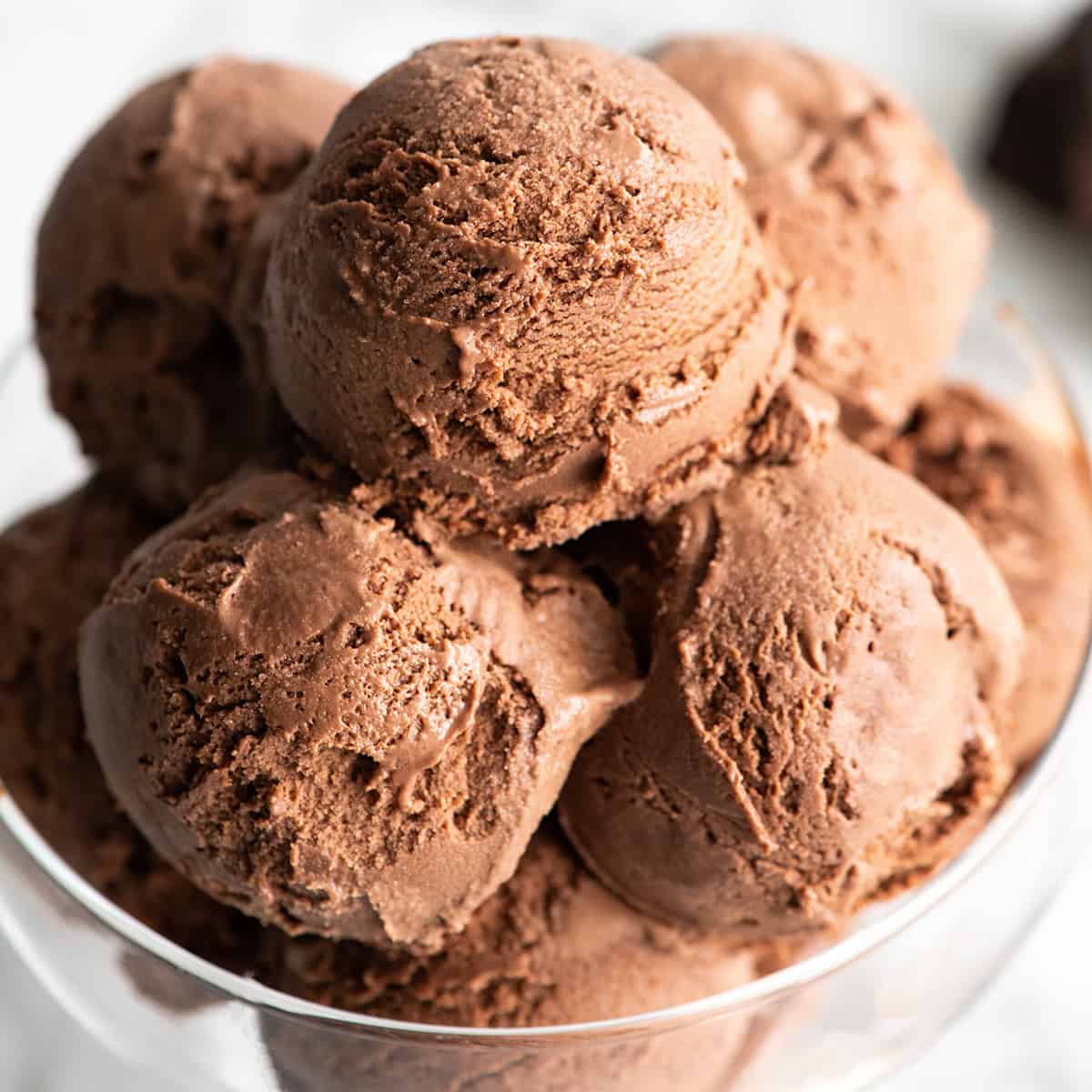 Rich, ultra-creamy, and chocolatey, this is the best homemade chocolate ice cream recipe ever! It's easy to make with only 7 ingredients (including two forms of chocolate), has a rich chocolate flavor, and is just as good as any ice cream shop! up close view of chocolate ice cream in a glass dish