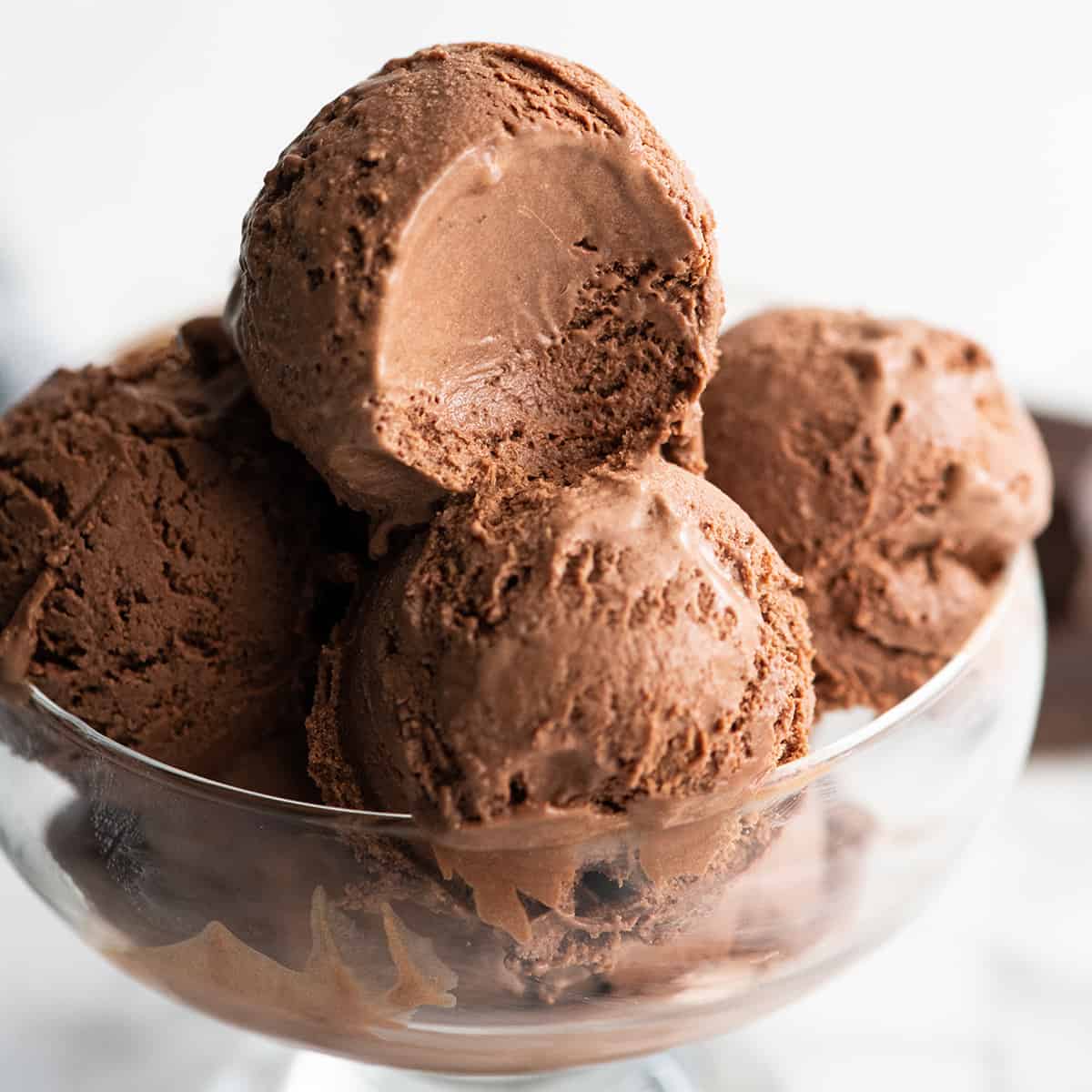 Rich, ultra-creamy, and chocolatey, this is the best homemade chocolate ice cream recipe ever! It's easy to make with only 7 ingredients (including two forms of chocolate), has a rich chocolate flavor, and is just as good as any ice cream shop! Front view of 4 scoops of homemade chocolate ice cream in a bowl