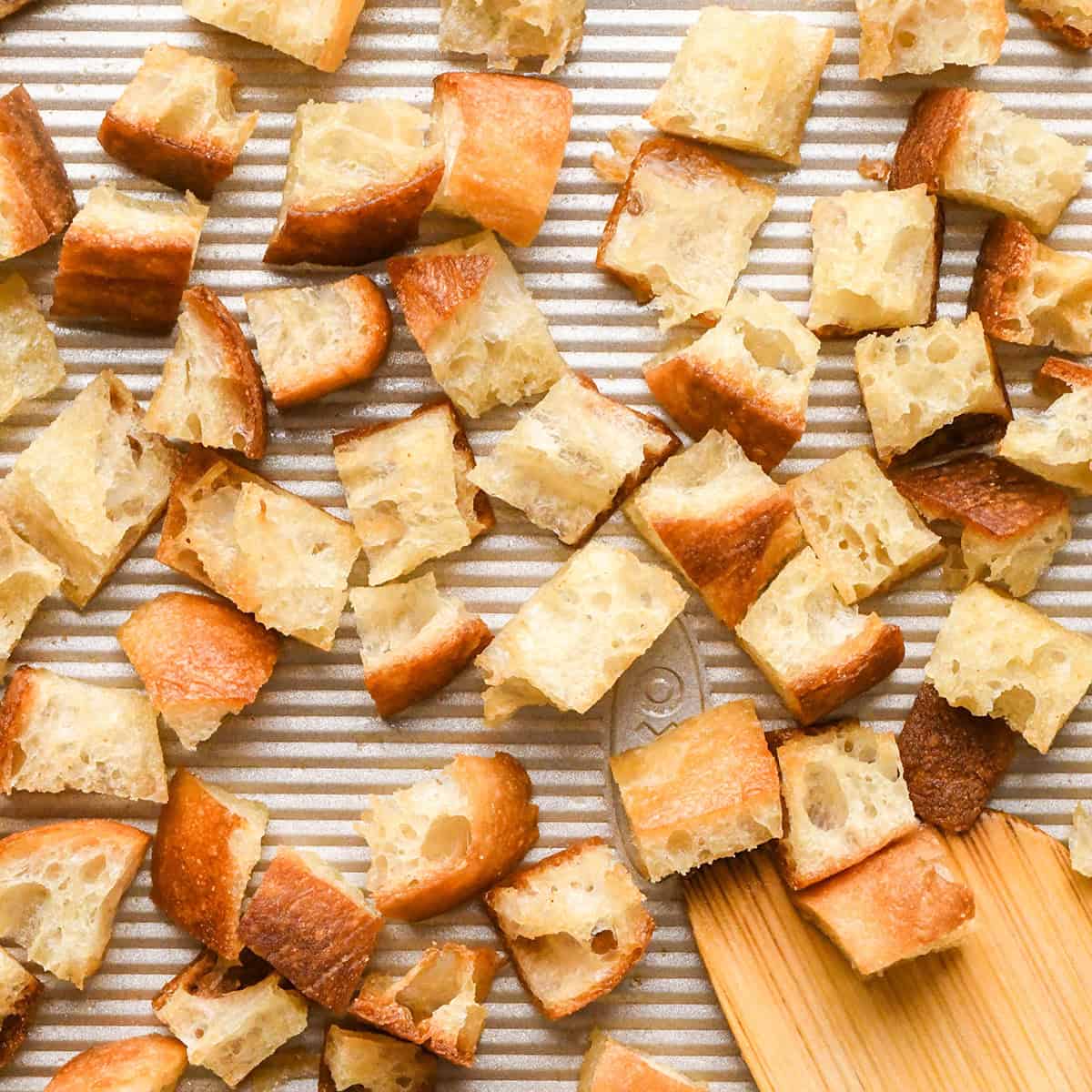 This Easy Homemade Croutons Recipe is made with 4 ingredients in 15 minutes! Learn how to make garlic croutons by following my step-by-step tutorial and video! They will transform any salad from good to WOW! #croutons #croutonrecipe #homemadecroutons #salad Homemade Croutons on a baking sheet