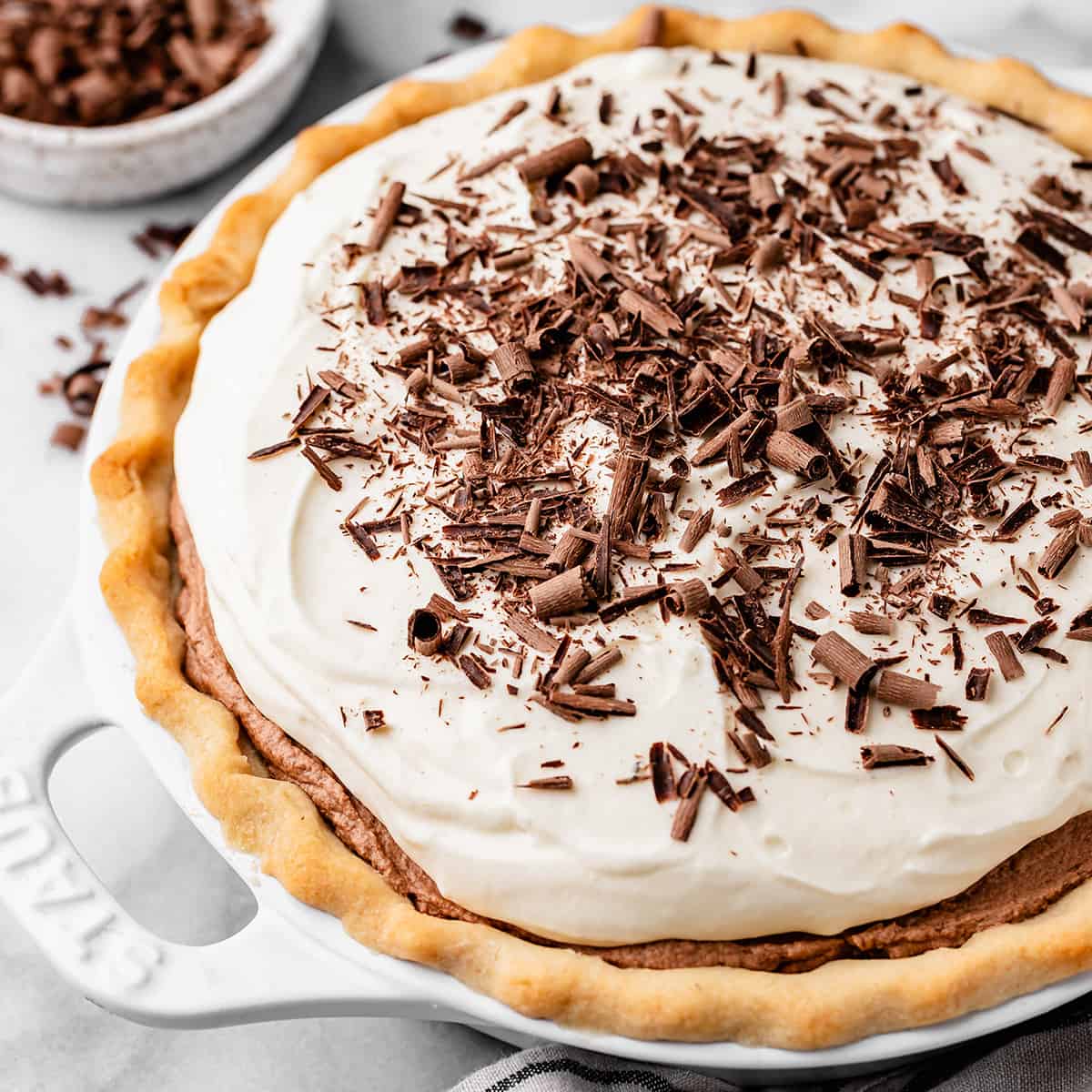 In this Homemade French Silk Pie recipe, a flaky pie crust is filled with a chocolate cream filling and topped with homemade whipped cream! This chocolate silk pie recipe is made from scratch and tastes even better than Baker's Square or Village Inn! #frenchsilkpie #frenchsilk #chocolatesilk french silk pie topped with whipped cream and chocolate shavings