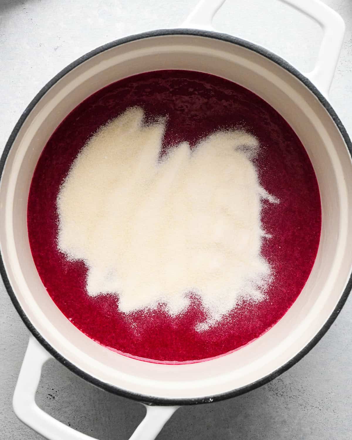 adding gelatin to homemade fruit snacks mixture in a saucepan