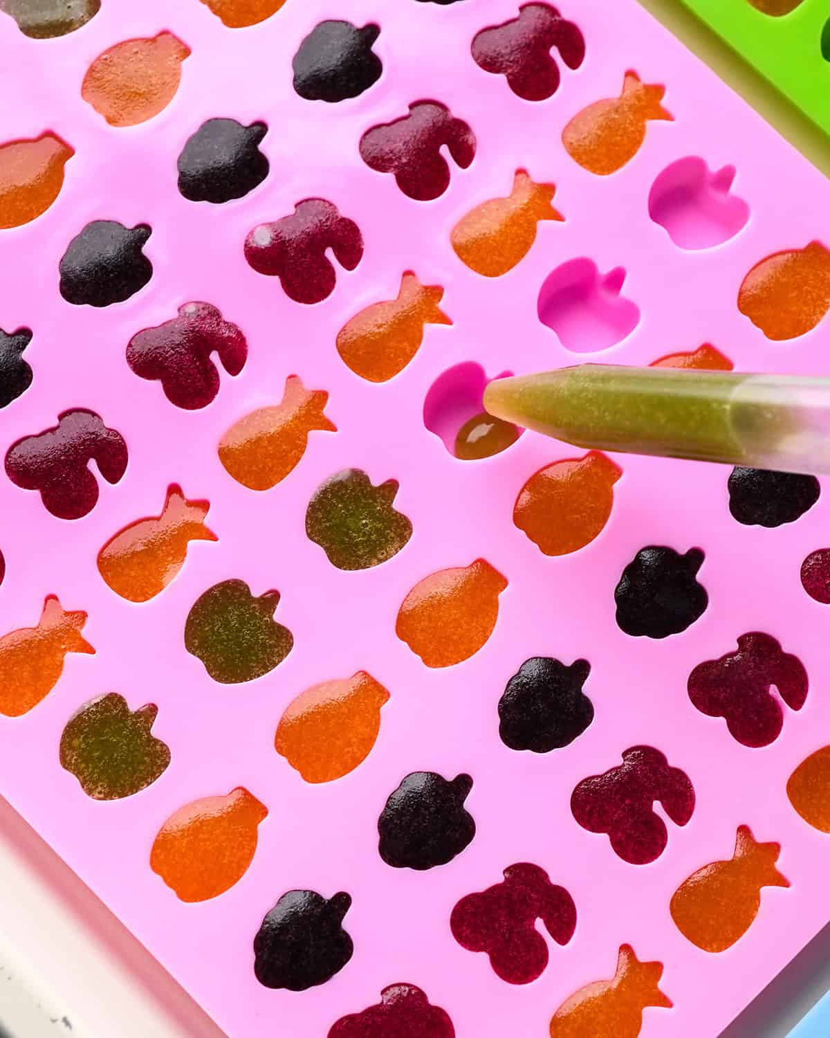 filling a silicone mold with homemade fruit snacks mixture
