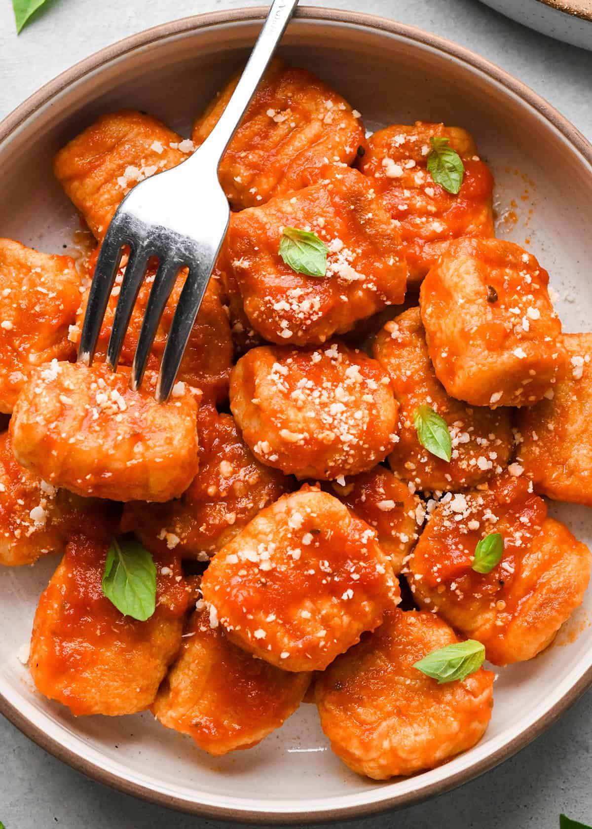 This Homemade Potato Gnocchi Recipe is made with only 5 ingredients and is SO much better than store bought varieties! Seriously we only ever eat homemade gnocchi! This version has cheddar cheese in the dough, setting it apart from all the others! It’s freezer friendly and beloved by kids and adults! #gnocchi #recipe #homemade #potatognocchi #fromscratch #healthyrecipe Potato Gnocchi in a bowl with marinara sauce and ad fork