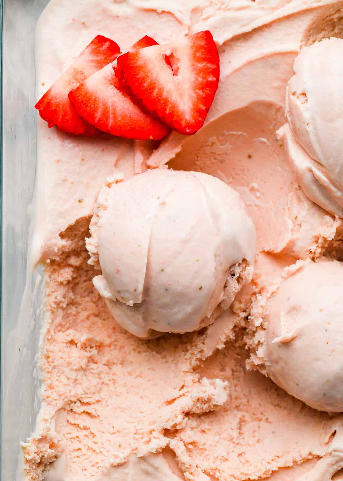 scoops of strawberry ice cream with fresh strawberries