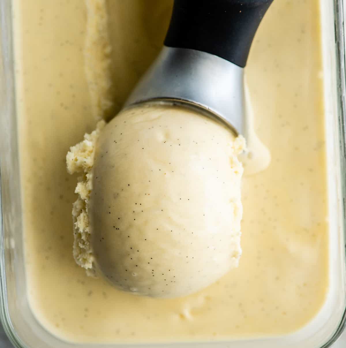 This homemade vanilla ice cream recipe is rich and creamy with a deep vanilla flavor. Watch the video and follow our step-by-step instructions to learn how to make this 5-ingredient vanilla bean ice cream recipe! up close overhead photo of vanilla bean nice cream being scooped