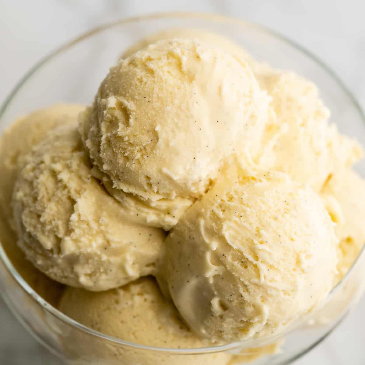 This homemade vanilla ice cream recipe is rich and creamy with a deep vanilla flavor. Watch the video and follow our step-by-step instructions to learn how to make this 5-ingredient vanilla bean ice cream recipe! scoops of homemade vanilla ice cream in a glass dish