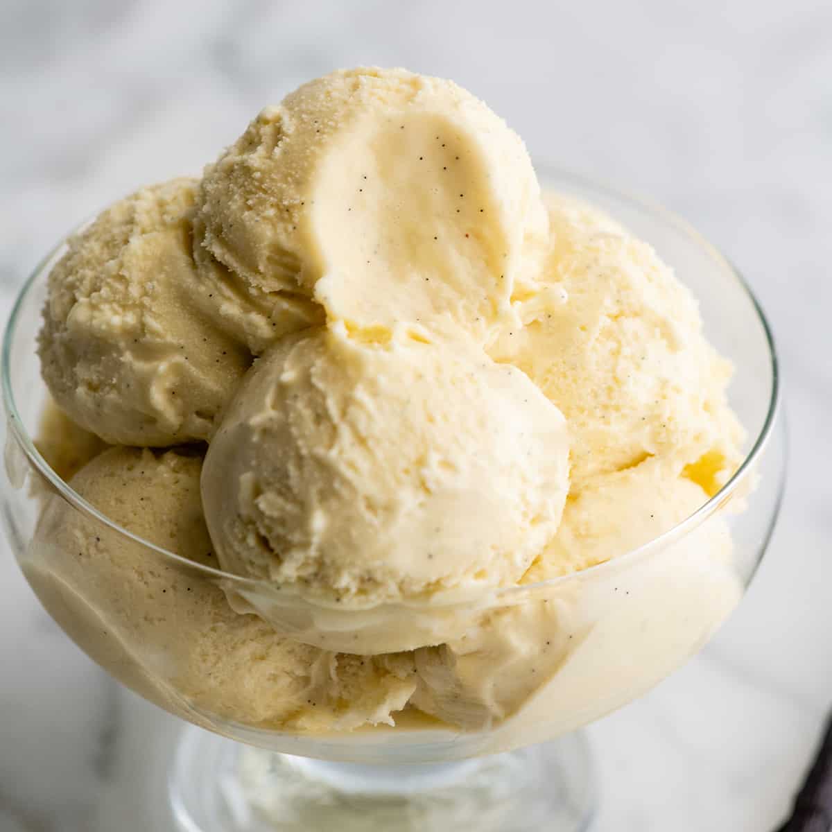 This homemade vanilla ice cream recipe is rich and creamy with a deep vanilla flavor. Watch the video and follow our step-by-step instructions to learn how to make this 5-ingredient vanilla bean ice cream recipe! best vanilla ice cream in a glass dish