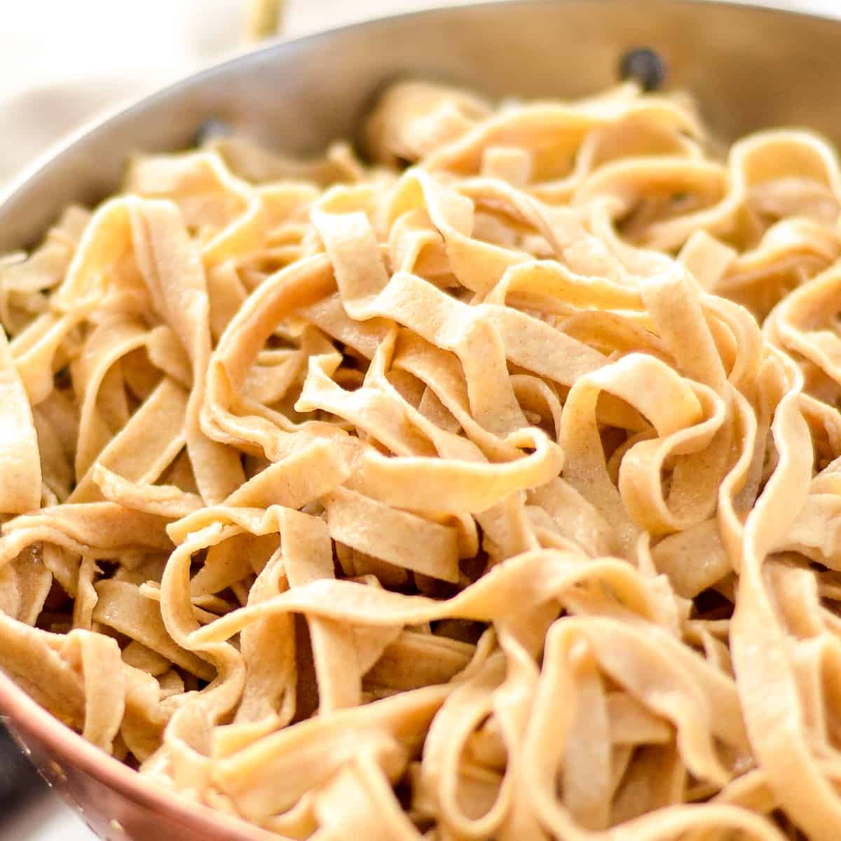 This Homemade Whole Wheat Pasta is the best homemade pasta recipe that taste's worlds better better than boxed varieties! Use it in a delicious main dish or serve it as a yummy side! #homemade #pasta #wholewheat #homemadenoodles #pastamaker a colander filled with Homemade Whole Wheat Pasta noodles after cooking