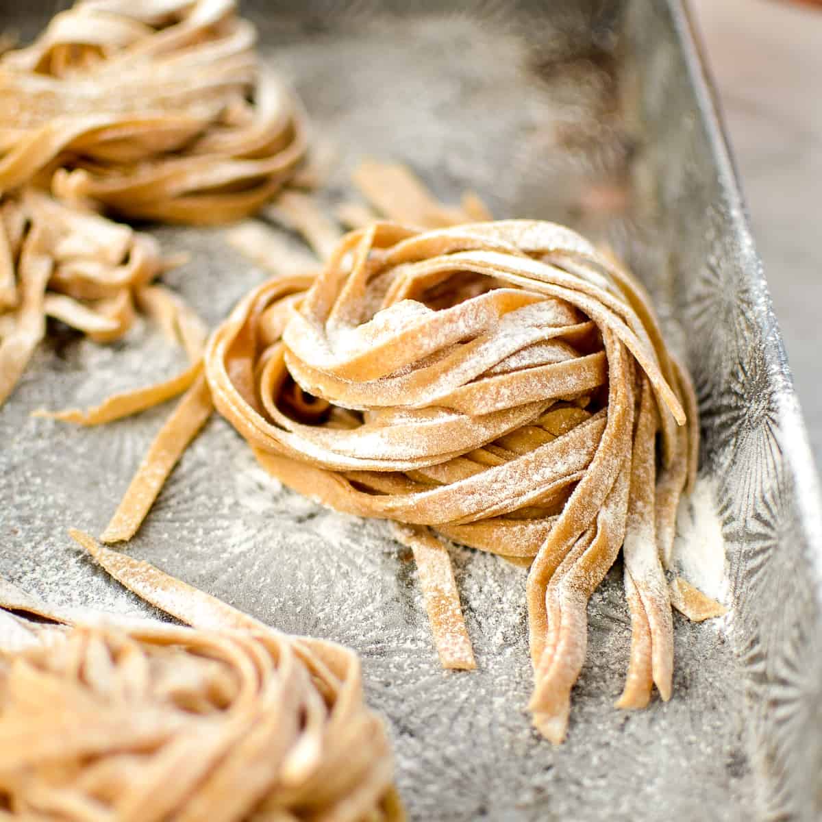 This Homemade Whole Wheat Pasta is the best homemade pasta recipe that taste's worlds better better than boxed varieties! Use it in a delicious main dish or serve it as a yummy side! #homemade #pasta #wholewheat #homemadenoodles #pastamaker front view of a stack of raw Homemade Whole Wheat Pasta
