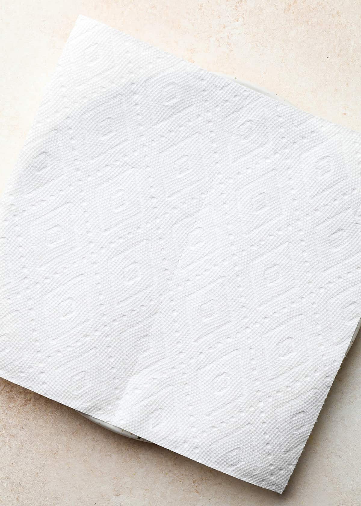 a paper towel on top of a plate to set baked bacon after cooking