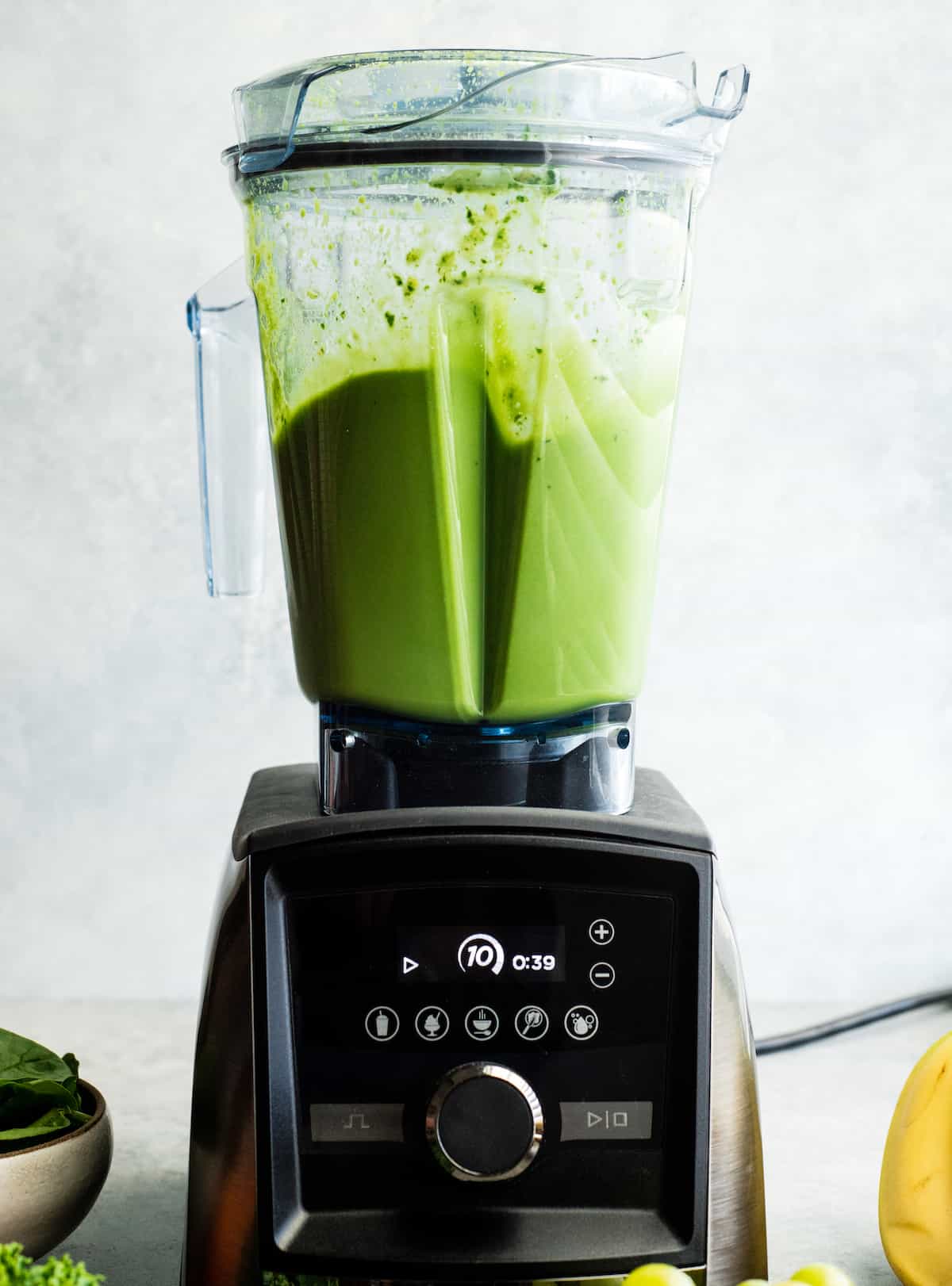 How to make the best green smoothie recipe! A simple green smoothie for beginners that is healthy, tastes amazing, and it's made with 4 ingredients in less than 5 minutes! Plus my tips on meal prepping smoothies! #greensmoothie #smoothie #smoothierecipe #greensmoothierecipe #kidfriendly Front view of a Vitamix A3500 blender blending a green smoothie