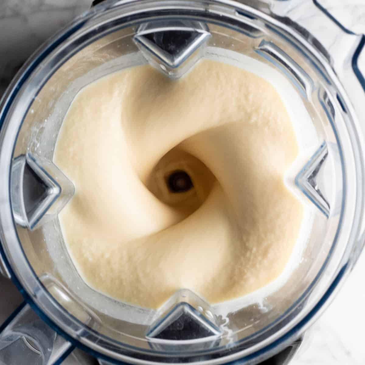 The BEST mango smoothie recipe! This healthy & easy mango smoothie is made in 5 minutes with 6 ingredients (including coconut milk, yogurt and banana)! It's ultra creamy and you can use fresh or frozen mango and easily make it dairy-free! #smoothie #mango #mangosmoothie #healthy #recipe #joyfoodsunshine overhead view of this mango banana smoothie being blended