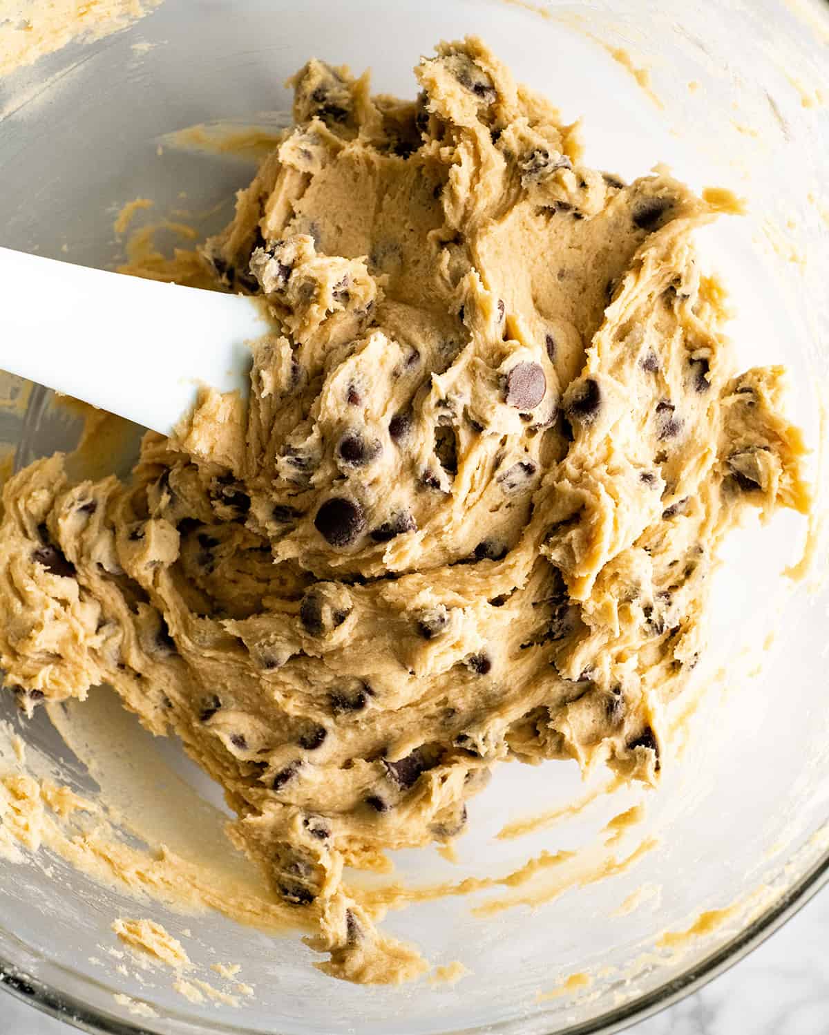 The BEST Chocolate Chip Skillet Cookie recipe! This ooey gooey, warm & melty skillet cookie (AKA: Pizookie) is completely irresistible. It's like eating warm cookie dough topped with vanilla ice cream, better than any restaurant version you've ever had! Plus it's easy to make & comes together in 20 minutes flat! #skilletcookie #pizookie #chocolatechipcookie #dessert #baking #joyfoodsunshine overhead view of the skillet cookie batter before baking