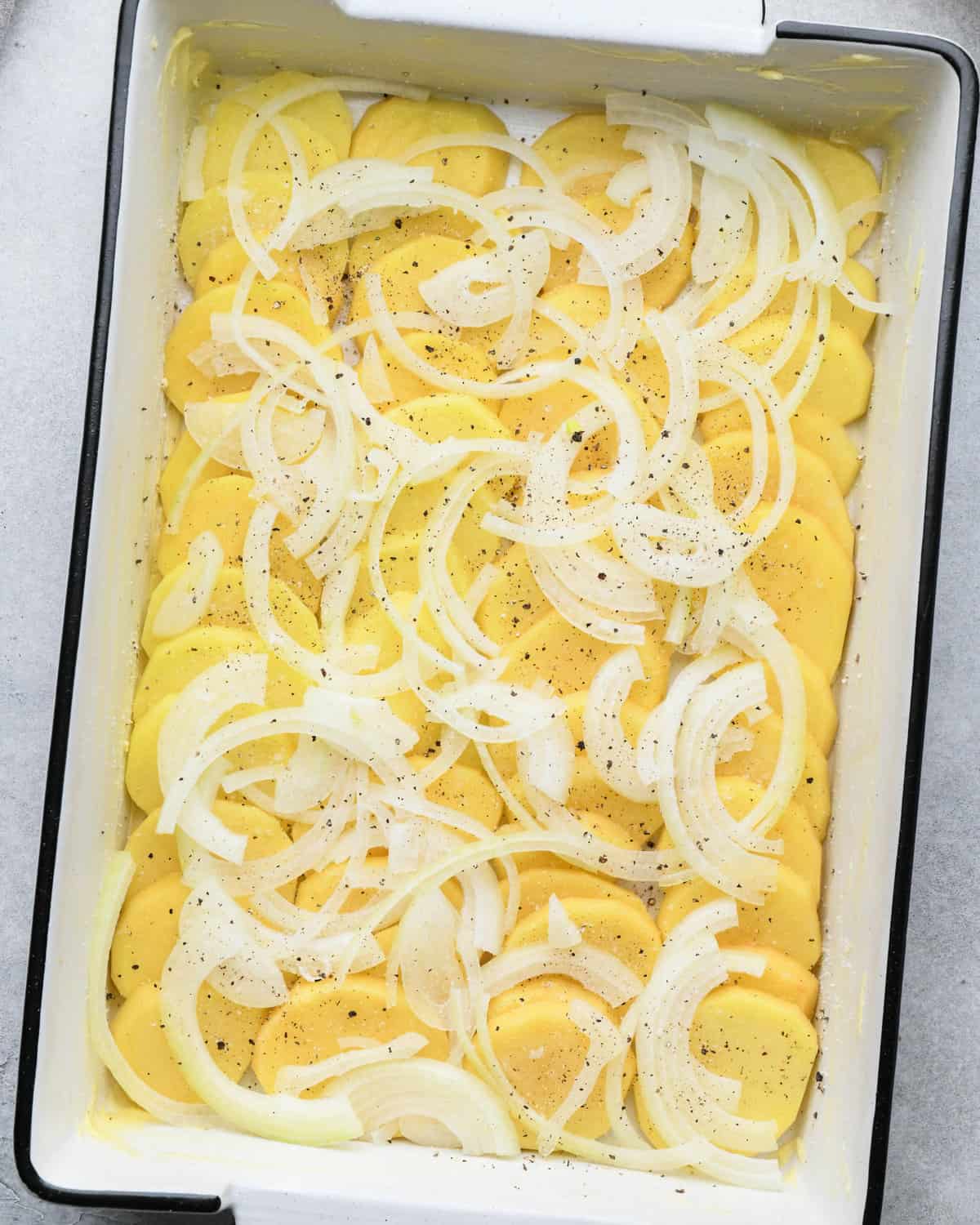 assembling au gratin potatoes in a baking dish
