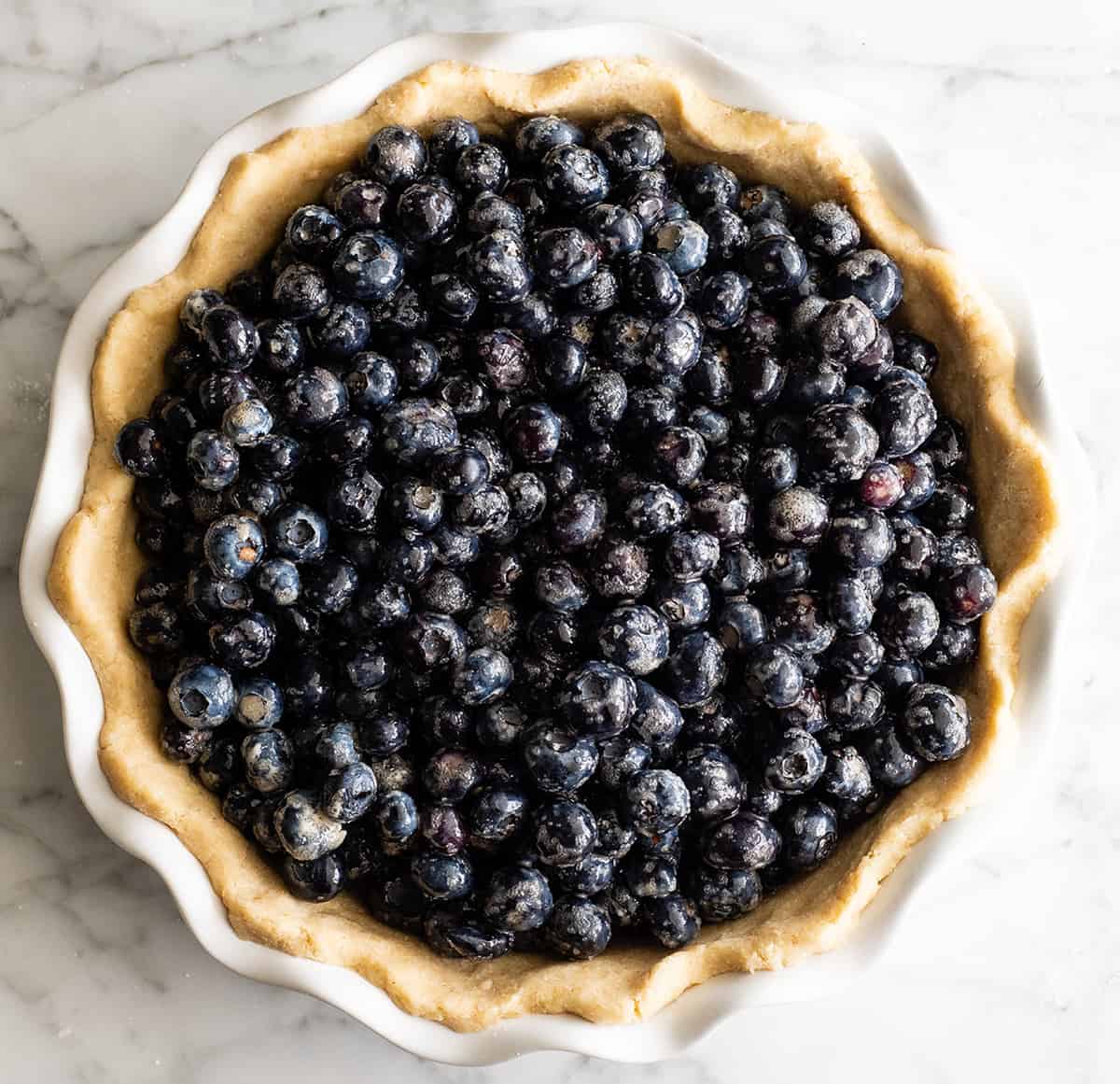 This is the best homemade Blueberry Pie Recipe you'll ever make! It's made from scratch with a fresh blueberry pie filling and NO cornstarch, and includes step-by-step instructions and photos! overhead photo showing how to make blueberry pie