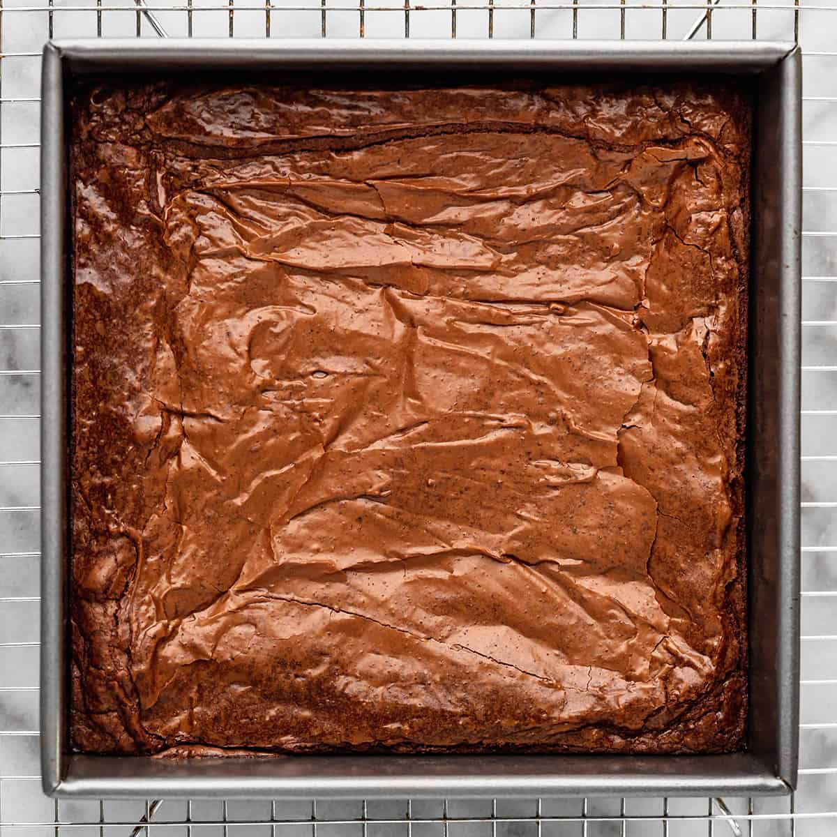 brownies in a pan cooling on a wire rack after baking, before being cut
