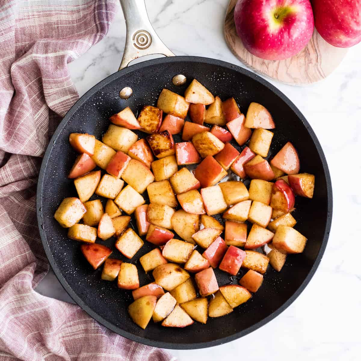 These Stovetop Sautéed Cinnamon Apples taste like a warm apple pie, but they come together in 5 minutes and are SO much healthier! This recipe is gluten-free, dairy-free, refined sugar free, vegan AND paleo! Perfect for breakfast, a snack, or dessert! #apples #stovetop #cinnamon #healthyrecipe #dessert #breakfast #snack #paleo #vegan #glutenfree #dairyfree #refinedsugarfree Overhead view of sautéed cinnamon apples in a non-stick fry pan