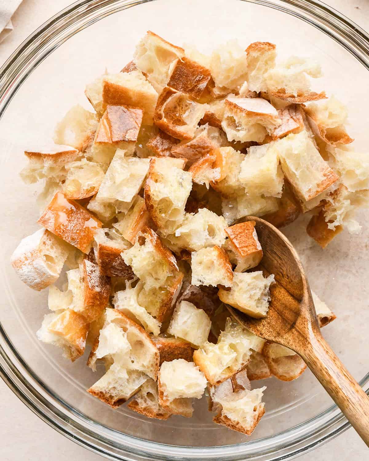 This Easy Homemade Croutons Recipe is made with 4 ingredients in 15 minutes! Learn how to make garlic croutons by following my step-by-step tutorial and video! They will transform any salad from good to WOW! #croutons #croutonrecipe #homemadecroutons #salad How to Make Croutons - stirring olive oil into bread cubes