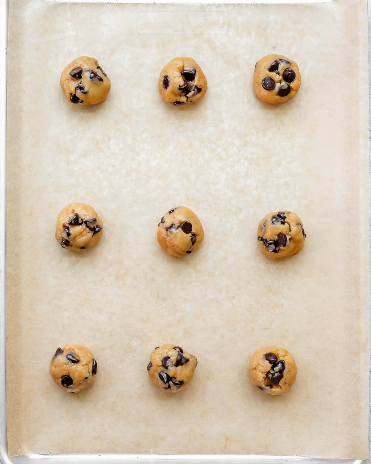 9 Dairy Free Chocolate Chip Cookie dough balls on a baking sheet before baking