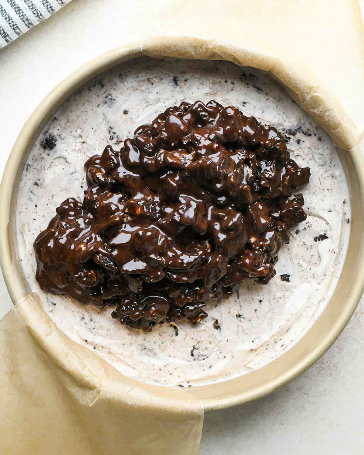 assembling an ice cream cake - oreo fudge sauce on top of ice cream layer before spreading out